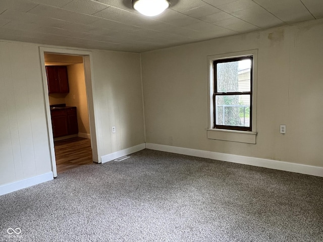 unfurnished room with baseboards, visible vents, and carpet