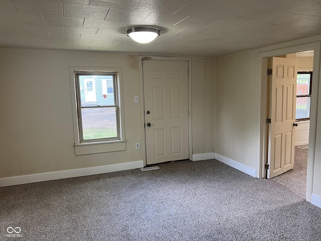 unfurnished room with a healthy amount of sunlight, baseboards, and carpet