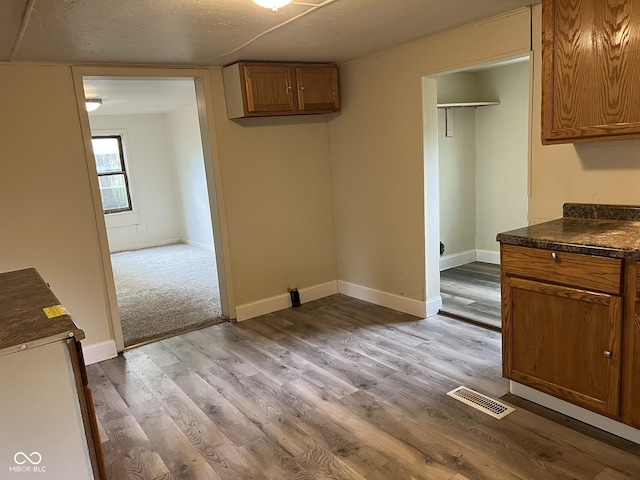 interior space with visible vents, dark countertops, brown cabinets, wood finished floors, and baseboards