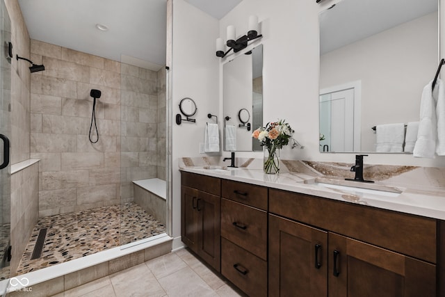 bathroom featuring a sink, tile patterned flooring, a shower stall, and double vanity