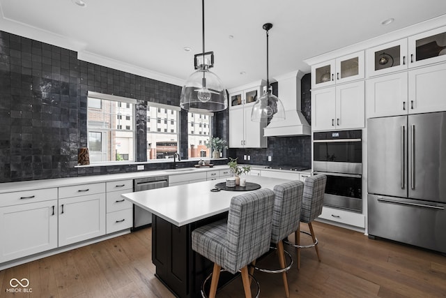 kitchen featuring crown molding, appliances with stainless steel finishes, a sink, light countertops, and custom range hood