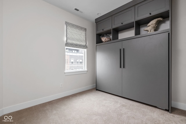 unfurnished bedroom featuring baseboards, light carpet, a closet, and visible vents
