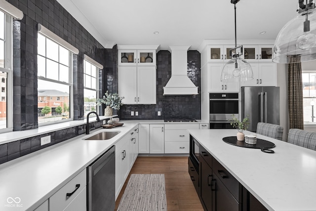 kitchen featuring dark wood-style flooring, custom exhaust hood, light countertops, a sink, and stainless steel appliances