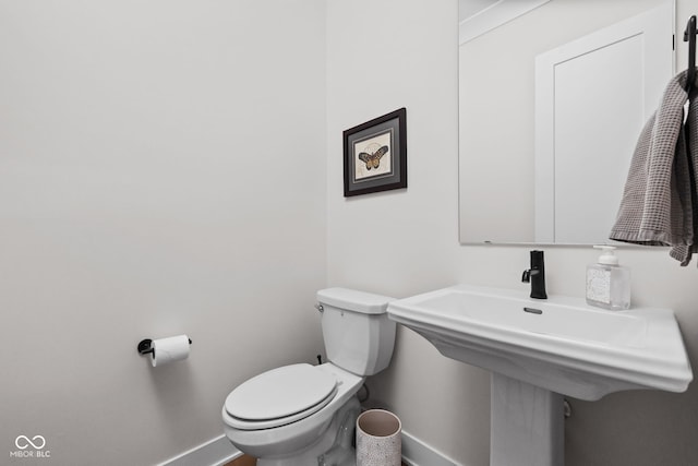 half bathroom with baseboards and toilet