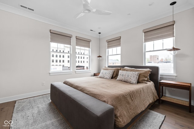 bedroom featuring visible vents, a ceiling fan, baseboards, and wood finished floors