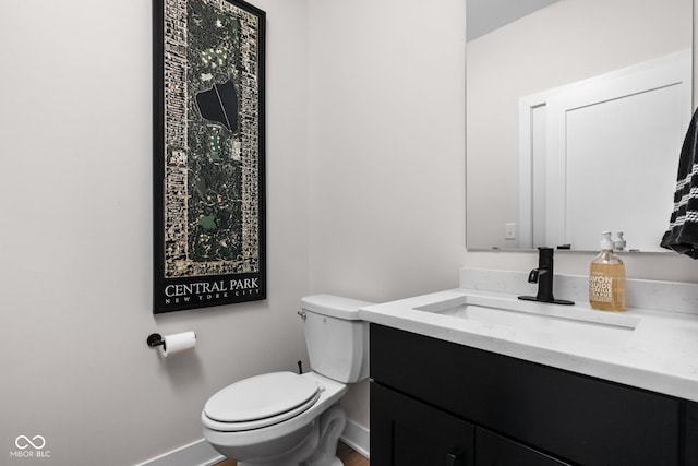 bathroom with baseboards, toilet, and vanity