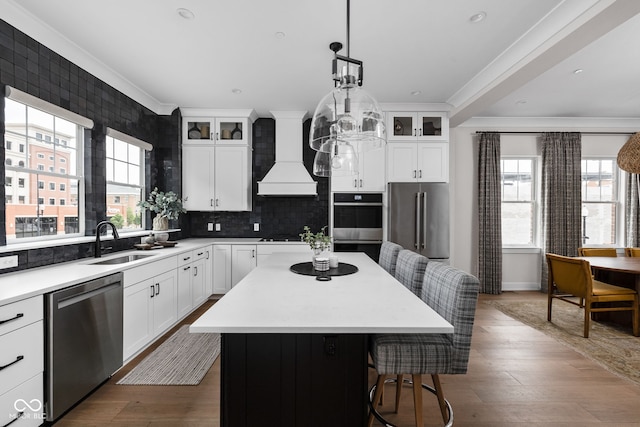 kitchen featuring custom exhaust hood, a kitchen island, a kitchen bar, a sink, and stainless steel appliances