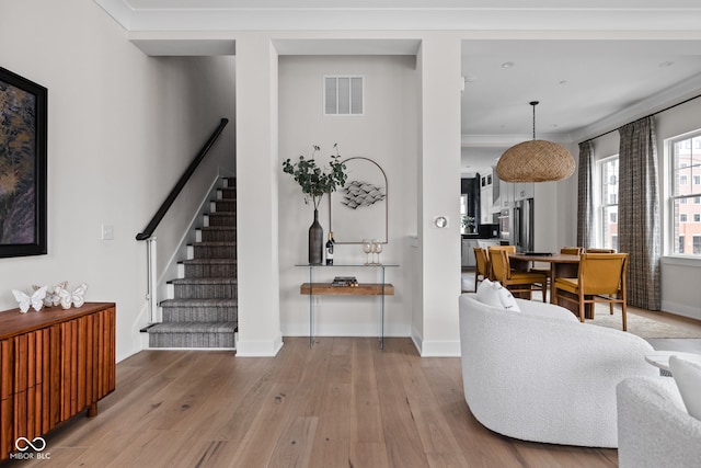 interior space with crown molding, stairs, baseboards, wood finished floors, and visible vents