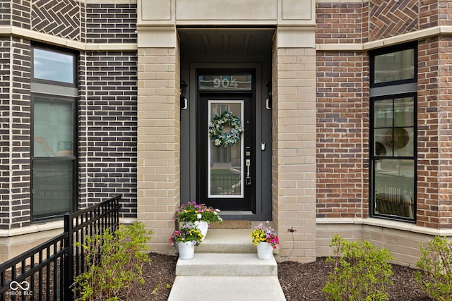 property entrance featuring brick siding and fence