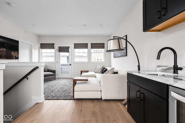 living area featuring baseboards, light wood finished floors, and wine cooler