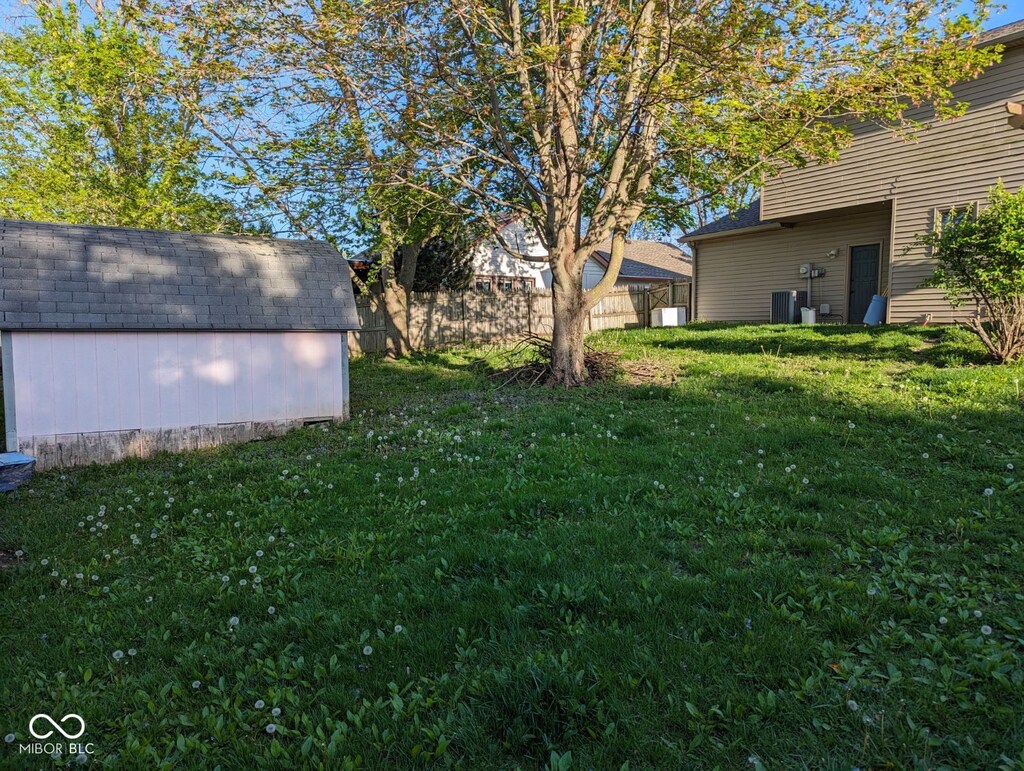 view of yard featuring a shed, an outbuilding, and central AC