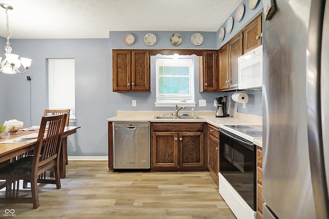 11620 E 75th St, Indianapolis, IN 46236 - kitchen featuring appliances with stainless steel finishes, a sink, a chandelier, light wood-style flooring, and a textured ceiling