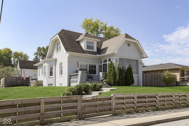 825 Iowa St, Indianapolis, IN 46203 - view of front of home with board and batten siding, brick siding, a fenced front yard, a shingled roof, and a front lawn
