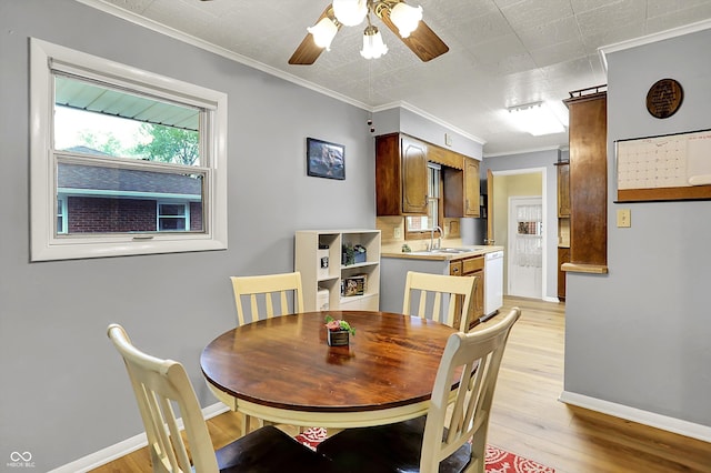 dining area featuring crown molding, baseboards, ceiling fan, and light wood-type flooring