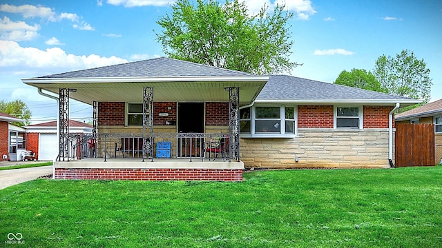 view of front facade with a front lawn, fence, covered porch, stone siding, and roof with shingles
