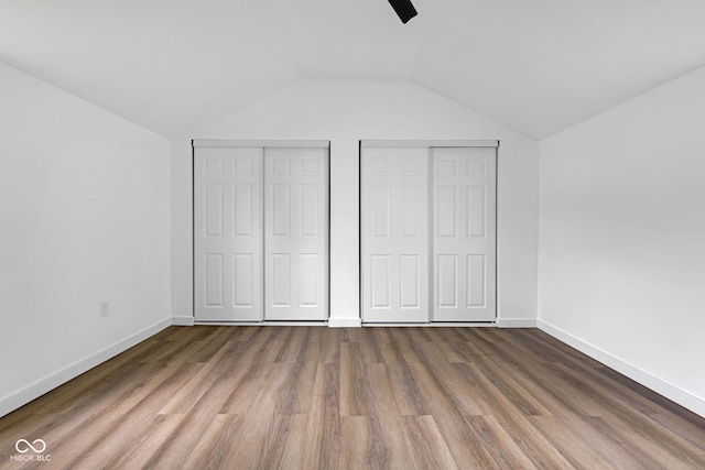 555 S Auburn St, Indianapolis, IN 46241 - unfurnished bedroom with baseboards, multiple closets, wood finished floors, and lofted ceiling