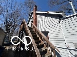 view of side of home featuring a chimney and stairs
