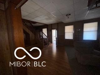 entrance foyer with a drop ceiling, stairs, and wood finished floors
