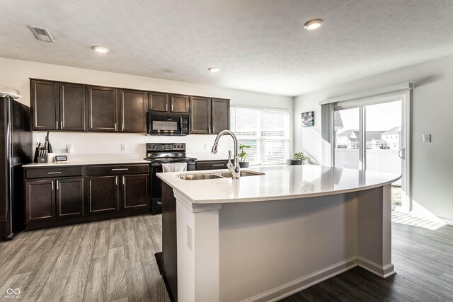 6559 Ambrosia Ln, Pendleton, IN 46064 - kitchen featuring visible vents, light wood-style floors, light countertops, a sink, and black appliances