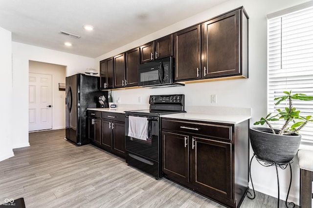 6559 Ambrosia Ln, Pendleton, IN 46064 - kitchen with dark brown cabinetry, visible vents, light countertops, black appliances, and light wood finished floors