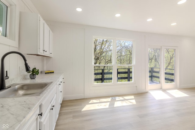 kitchen with light wood-style floors, a sink, white cabinets, and recessed lighting