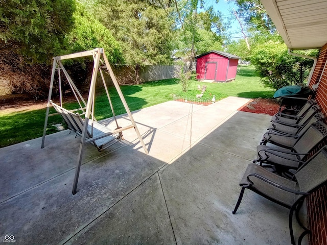 view of patio / terrace with a storage unit, a playground, a fenced backyard, and an outbuilding