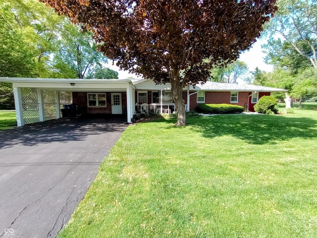 ranch-style home featuring a front yard, an attached carport, brick siding, and driveway