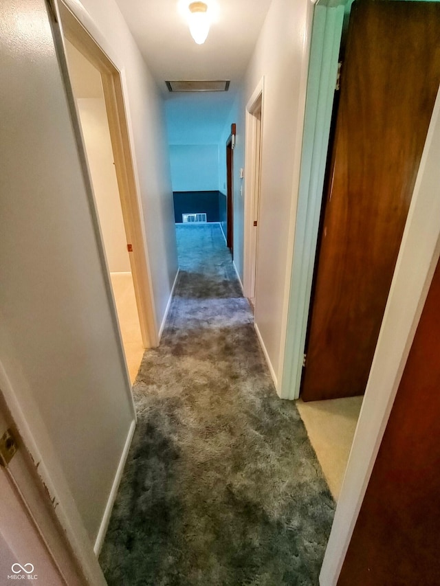 hallway featuring baseboards, visible vents, and carpet
