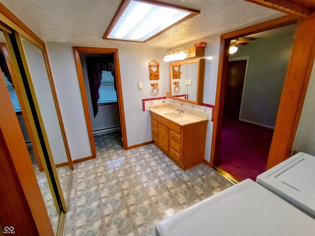 bathroom with a baseboard radiator, a textured ceiling, baseboards, tile patterned floors, and vanity