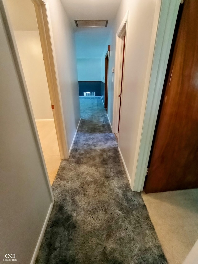 hallway with attic access, visible vents, baseboards, and carpet floors