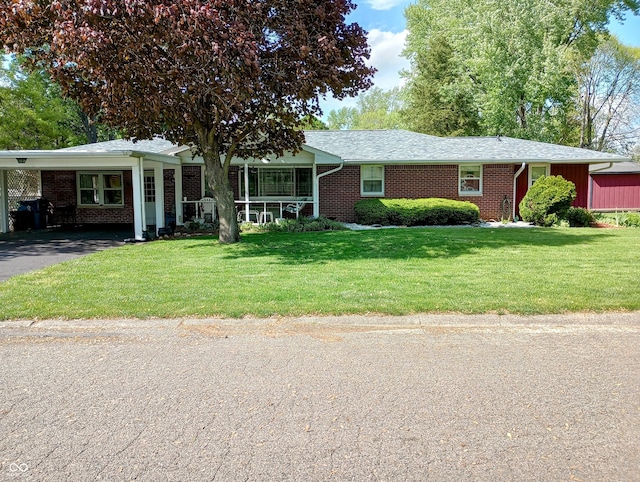 single story home featuring driveway, brick siding, a front yard, and a carport