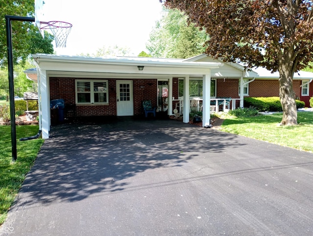 ranch-style house with a front yard, a carport, brick siding, and driveway