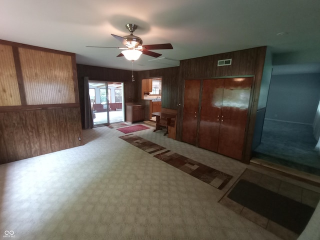 unfurnished bedroom with a closet, visible vents, wood walls, and access to exterior