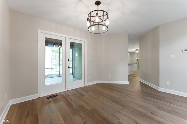 unfurnished dining area with wood finished floors, a chandelier, and baseboards