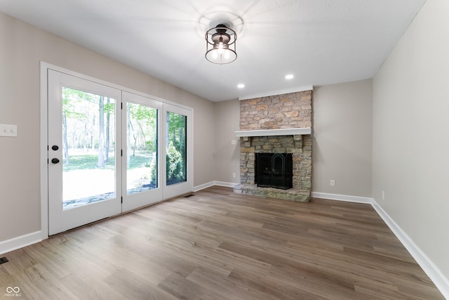 unfurnished living room featuring wood finished floors, a fireplace, baseboards, and recessed lighting