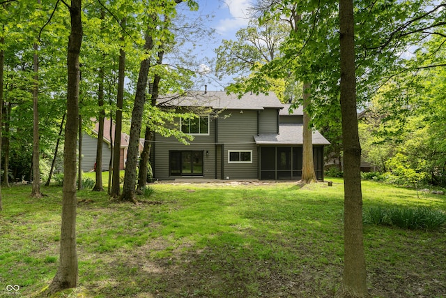 rear view of property with a sunroom, a lawn, and a shingled roof