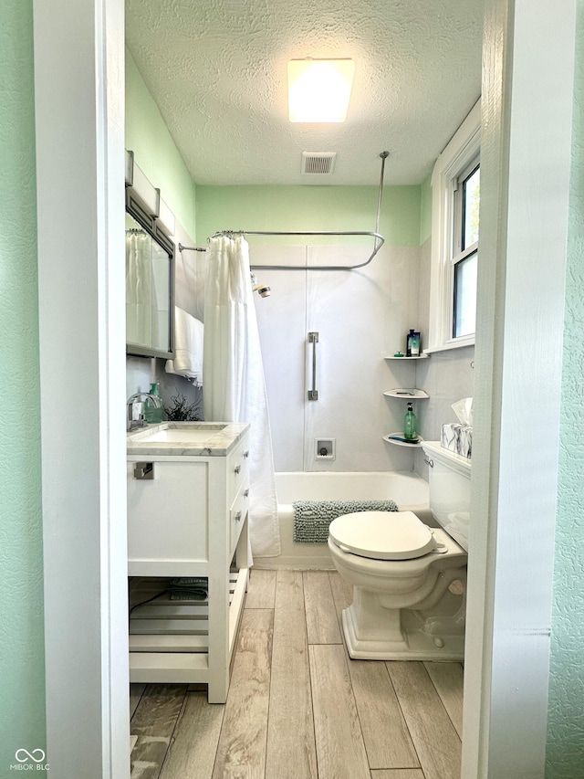 2119 S Garfield Dr, Indianapolis, IN 46203 - bathroom featuring wood finished floors, toilet, a textured ceiling, shower / tub combo with curtain, and vanity