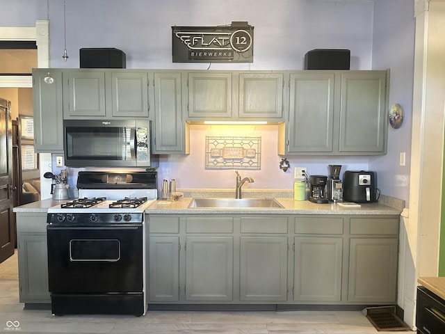 2119 S Garfield Dr, Indianapolis, IN 46203 - kitchen featuring stainless steel microwave, black gas range oven, a sink, and light countertops