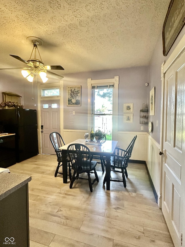 2119 S Garfield Dr, Indianapolis, IN 46203 - dining space with a textured ceiling, a wainscoted wall, healthy amount of natural light, light wood-type flooring, and a ceiling fan