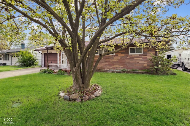 ranch-style house with an attached garage, a front lawn, stone siding, and concrete driveway