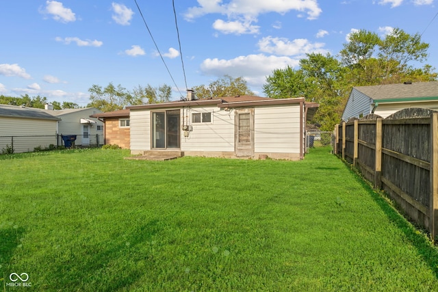 back of house featuring a fenced backyard, entry steps, and a lawn