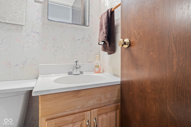 bathroom featuring vanity, toilet, and wallpapered walls