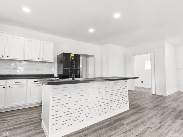 1630 N Granville Ave N, Muncie, IN 47303 - kitchen with dark countertops, light wood finished floors, white cabinetry, black refrigerator, and a center island with sink