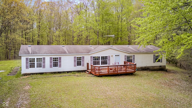 rear view of house featuring a shingled roof, a deck, crawl space, a view of trees, and a yard