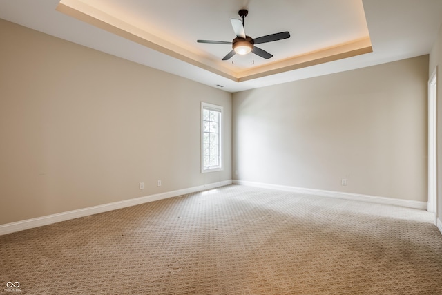 spare room featuring light carpet, a raised ceiling, and ceiling fan