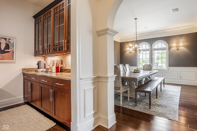 bar with dark wood-style flooring, arched walkways, decorative light fixtures, a chandelier, and tasteful backsplash