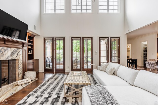 living area featuring a healthy amount of sunlight, built in features, a towering ceiling, and a premium fireplace