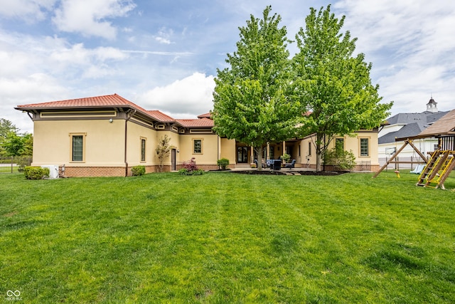 back of house with a yard, stucco siding, and a tile roof