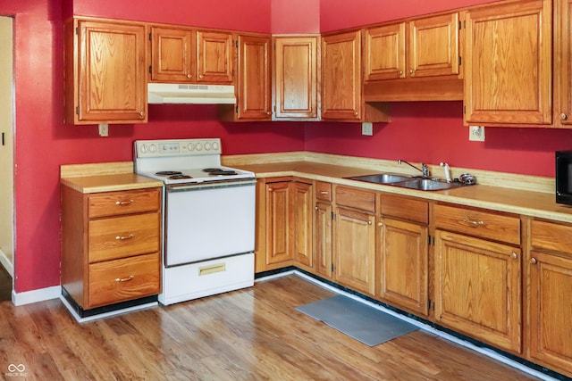 1020 E Sixth St, Greenfield, IN 46140 - kitchen with electric stove, under cabinet range hood, a sink, light countertops, and brown cabinetry