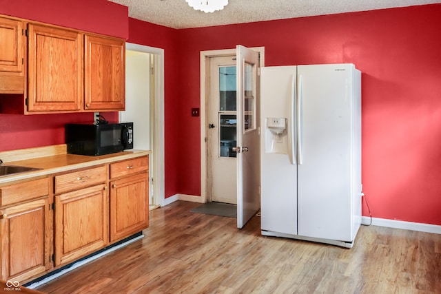 1020 E Sixth St, Greenfield, IN 46140 - kitchen with white fridge with ice dispenser, black microwave, light wood-type flooring, light countertops, and a textured ceiling